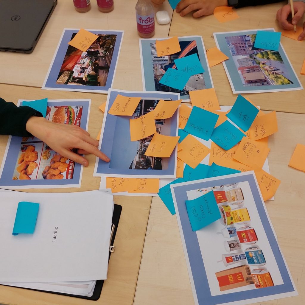 Group activity: participants annotate food photos with orange and blue sticky notes on a table during a workshop.