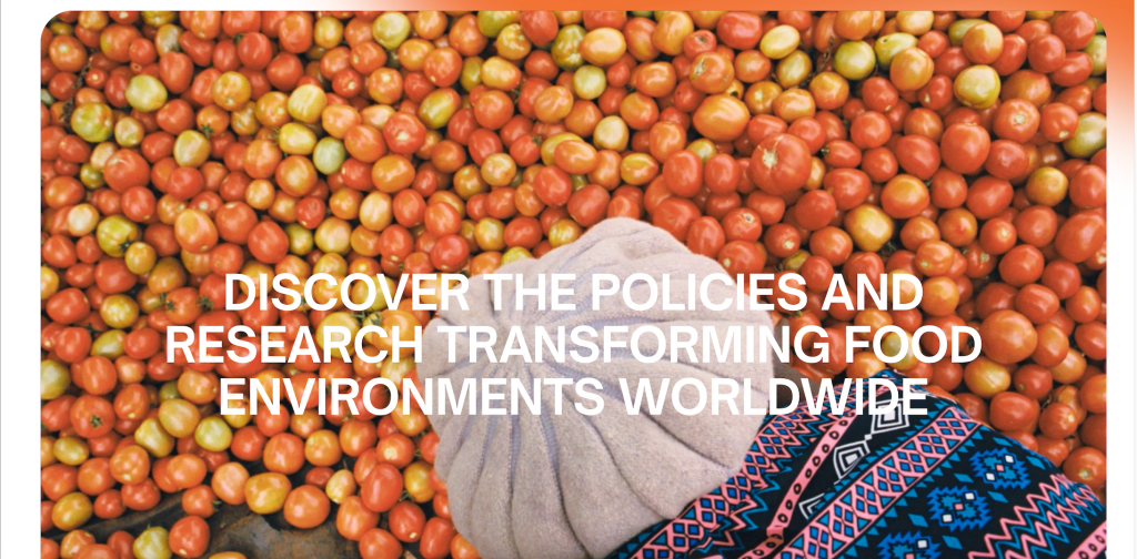 Person in a patterned garment among crates of red and green cherry tomatoes; bold headline invites discovering policies shaping food environments.